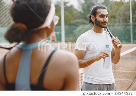 Two tennis players drinking a water on a tennis court before the match Two tennis players drinking a water on a tennis court before the match 84544582