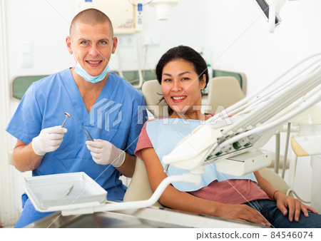 Dentist and happy patient sitting in dental chair Dentist and happy patient sitting in dental chair 84546074