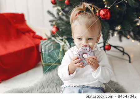 Little girl eating donuts in a festive room. Little girl eating donuts in a festive room. 84547042