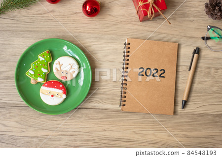 2022 notebook, black, Christmas cookies and pen on wood table, Top view and copy space. Xmas, Happy New Year, Goals, Resolution, To do list, Strategy and Plan concept 84548193