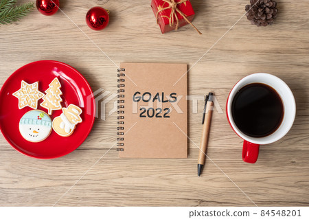 2022 GOAL with notebook, black coffee cup, Christmas cookies and pen on wood table. Xmas, Happy New Year, Resolution, To do list, Strategy and Plan concept 84548201