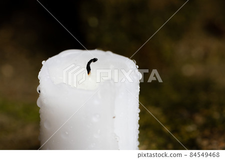 An extinguished candle after the rain. Black wick and drops of water on the wax. Front view. An extinguished candle after the rain. Black wick and drops of water on the wax. Front view. 84549468