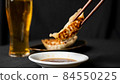 Photo of dumplings on soy sauce with chopsticks 84550225