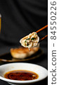 A photo of dumplings lifted with chopsticks showing a cross section 84550226