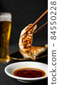 Photo of dumplings on soy sauce with chopsticks 84550228