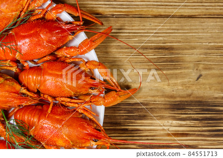 Boiled crayfish in plate on wooden table. Top view 84551713