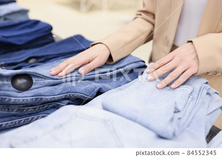 Woman choose jeans in trendy store, decide between different colours 84552345