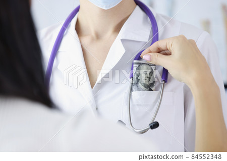 Woman patient put banknote in doctors pocket on appointment for better service Woman patient put banknote in doctors pocket on appointment for better service 84552348
