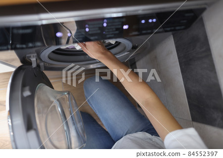 Woman hands load washing machine with dirty clothes or taking out clean 84552397