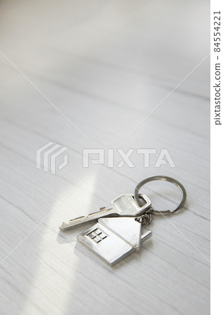 Silver key with silver house figure on white wooden background, buying new house real estate concept copy space 84554221