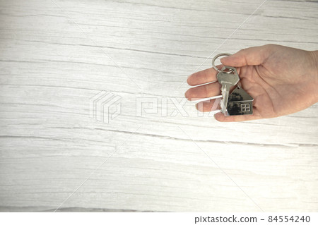 realtor female hand holding new door key to new house on white background top view with copy space, buying new home concept 84554240