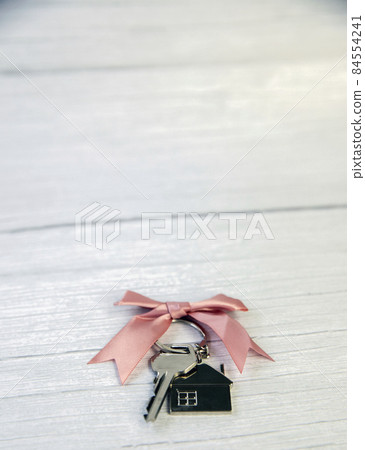 New keys of a house silver with keychain of little house top view with copy space and white wooden background, New keys of a house silver with keychain of little house top view with copy space and white wooden background, 84554241