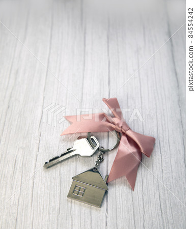 New keys of a house silver with keychain of little house top view with copy space and white wooden background, 84554242