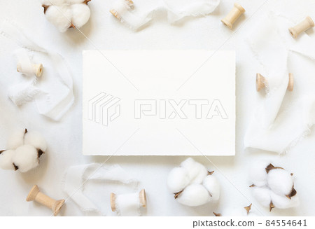 Blank card on white table with cotton flowers top view Blank card on white table with cotton flowers top view 84554641