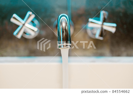Washing hands in bathroom sink at home. Open chrome metal silver tap with white ceramic bath in luxury bathroom wall background 84554662