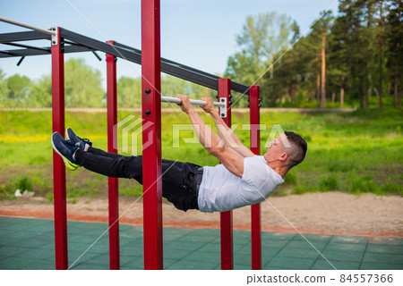 Caucasian man doing a back plank on the uneven bars. Workout on the sports ground. 84557366