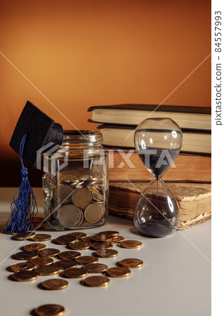 Jar with coins, graduation hat and hourglass. Savings and education theme Jar with coins, graduation hat and hourglass. Savings and education theme 84557993