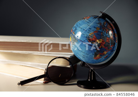 Global education concept. Magnifier and globe with books 84558046