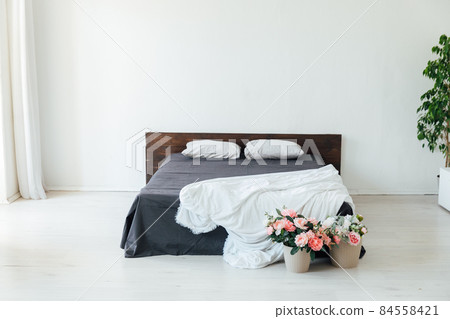interior of a white bedroom with a bed and flowers 84558421