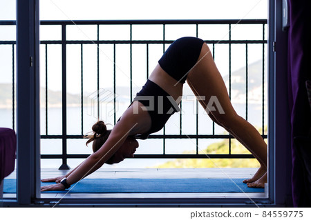 Young fitness woman doing morning yoga practice at the balcony near the sea 84559775
