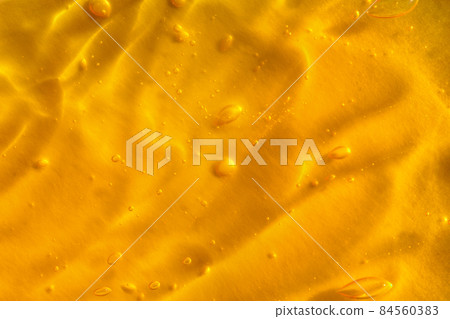 Texture of transparent yellow gel with air bubbles and waves on orange background. Concept of skin moisturizing, body care and prevention of covid19. Liquid beauty product closeup. Backdrop, flat lay Texture of transparent yellow gel with air bubbles and waves on orange background. Concept of skin moisturizing, body care and prevention of covid19. Liquid beauty product closeup. Backdrop, flat lay 84560383