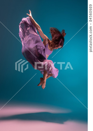 Young adorable flexible contemp dancer in lilac dress dancing isolated on gradient blue white background in neon. Young adorable flexible contemp dancer in lilac dress dancing isolated on gradient blue white background in neon. 84560989