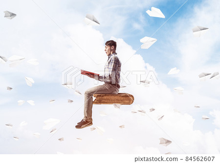 Handsome man student reading book and paper planes flying around 84562607