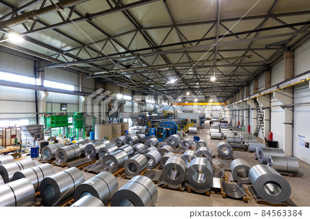 Photo of roll of painted galvanized steel sheet at cutting machine. Industrial machine for metal 84563384