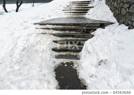 Concrete stone staircase covered with dirty deep slippery snow after blizzard snowstorm snowfall at city pedestrian walkway. Slide fall injury danger slip steps. Winter cold season weather 84563680