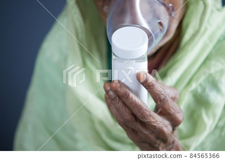senior women hand hold a nebulizer against light gray background senior women hand hold a nebulizer against light gray background 84565366