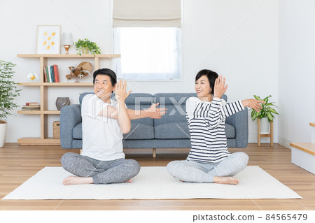 Middle-aged couple doing gymnastics in the living room at home Middle-aged couple doing gymnastics in the living room at home 84565479