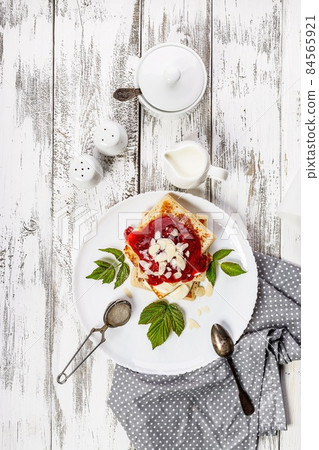 Traditional delicious pancakes with strawberry jam. Tasty breakfast. Homemade pancakes with jam on a white rustic background. Serving white tableware. Sweet dessert. Top view. Vertical shot 84565921
