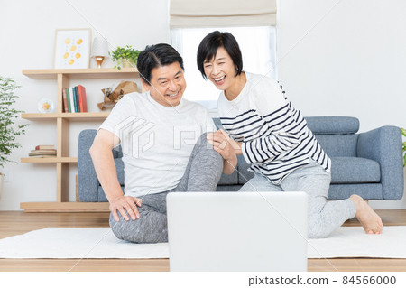 Middle-aged couple doing gymnastics online in their living room 84566000