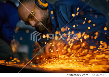 Man working with electric steel cutter machine near sparks. Man working with electric steel cutter machine near sparks. 84567485