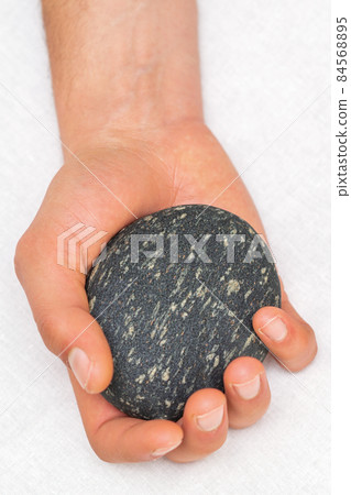 Hand of masseur holding massage stone on white background, top view. Hand of masseur holding massage stone on white background, top view. 84568895