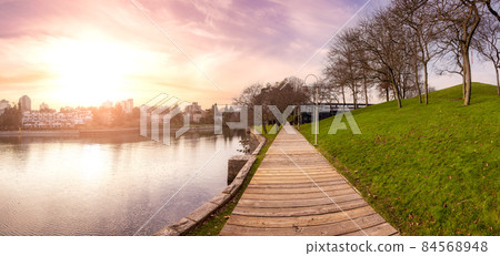 Wooden path in a modern city park during sunny fall season. 84568948
