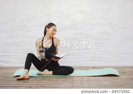 Woman practicing advanced yoga by the water 84571092