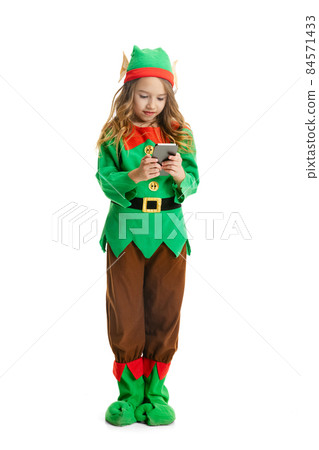 Cute smiling little girl dressed like funny gnome or elf using phone isolated over white studio background. Winter, holiday, christmas concept 84571433