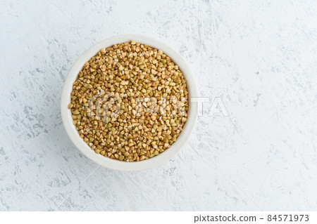 Green buckwheat in white bowl on white background. Dried cereals in cup, vegan food 84571973