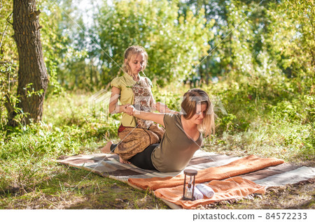 Experienced masseuse applies her massage skills on her client on the ground. Experienced masseuse applies her massage skills on her client on the ground. 84572233