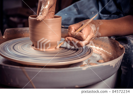 Master-ceramist creates a clay pot on a potter's wheel. Hands of potter close up. Ancient craft and pottery handmade work 84572234
