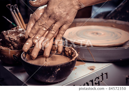 Artisan girl molding a vase of clay on a potter's wheel. Handicraft industry. Close-up. Artisan girl molding a vase of clay on a potter's wheel. Handicraft industry. Close-up. 84572350