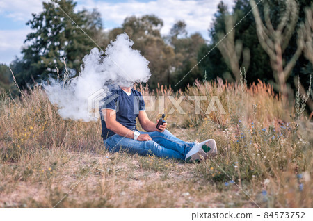 Stylish vape man vaping an e-cigarette. The man smokes. Stylish vape man vaping an e-cigarette. The man smokes. 84573752