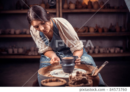 Young female potter working on a potter's wheel. 84573760