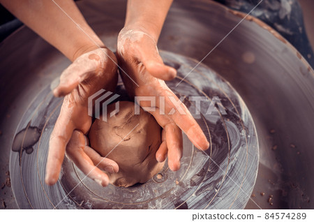 Potter master woman at his wheel creating a new masterpiece. National craft. Close-up. Potter master woman at his wheel creating a new masterpiece. National craft. Close-up. 84574289