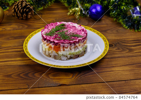 Traditional russian salad "Herring under a fur coat" (shuba) and Christmas decorations on wooden table Traditional russian salad "Herring under a fur coat" (shuba) and Christmas decorations on wooden table 84574764