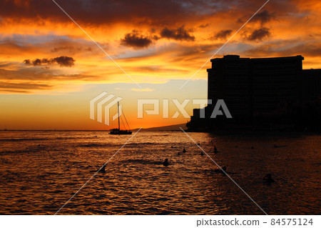 Orange sunset with a boat and the shape of skyscraper on the Ocean 84575124