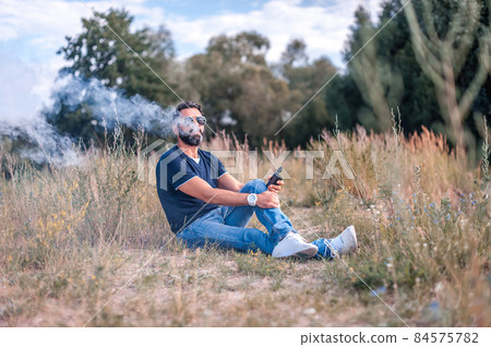 Confident smoker vaping an e-cigarette. Vaping concept. 84575782