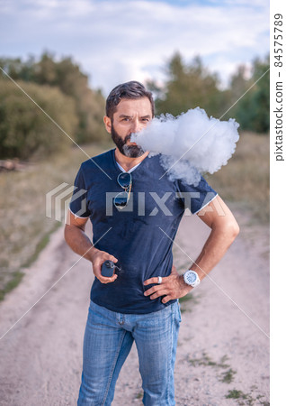 Bearded smoker smoke electronic smoke device and exhals smoke cloud. Getting rid of nicotine addiction. Bearded smoker smoke electronic smoke device and exhals smoke cloud. Getting rid of nicotine addiction. 84575789