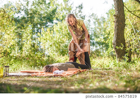 Massage trainer thuroughly massages a girl on the grass. Massage trainer thuroughly massages a girl on the grass. 84575819